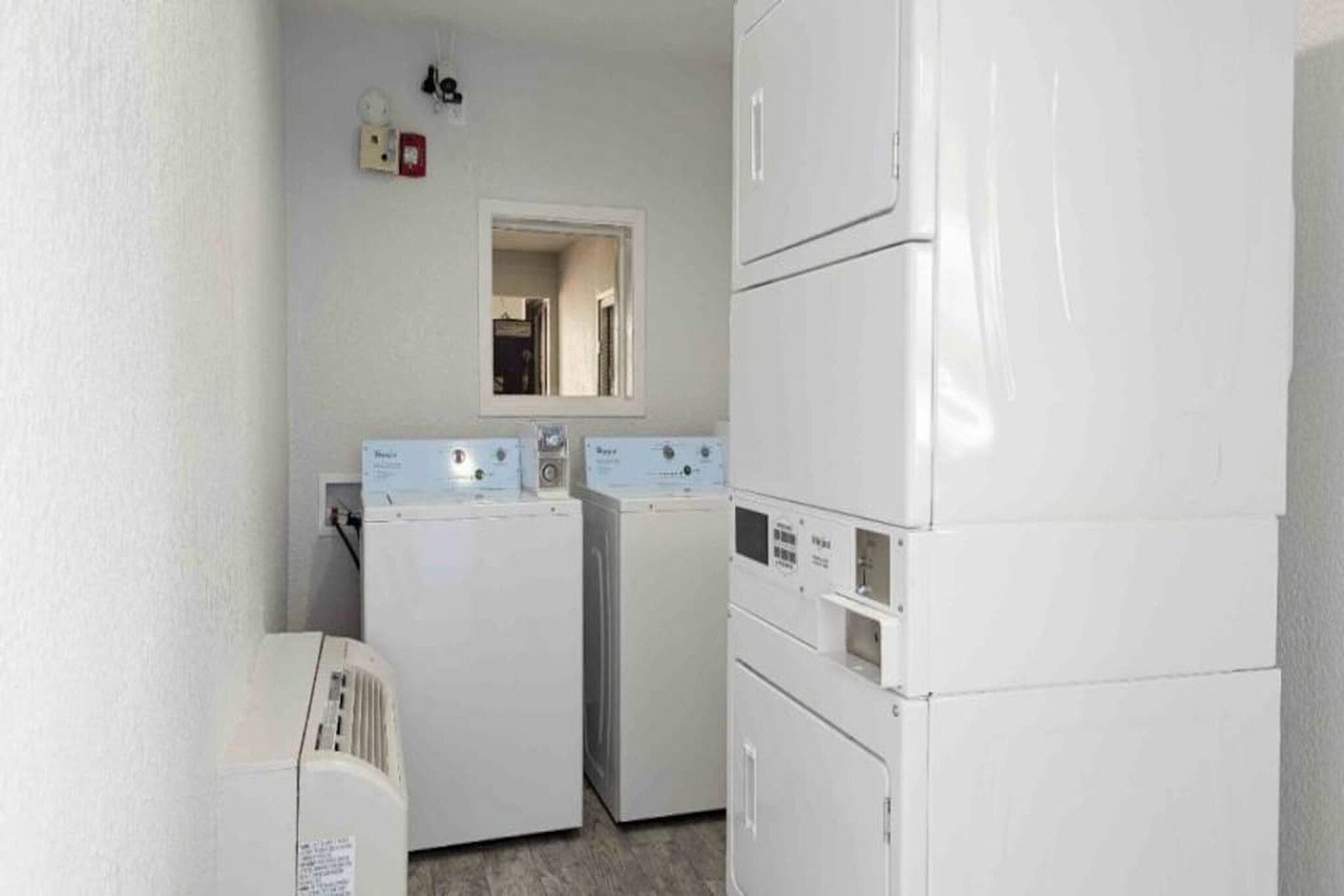 A laundry room with two stacked washing machines and a dryer.