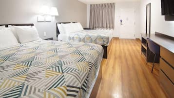 Une chambre d’hôtel avec deux lits, un bureau et une télévision.
