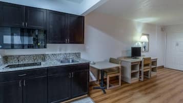 A compact kitchen with dark cabinets, a granite countertop, and a dining area with a table and chairs.