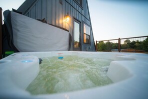 A hot tub with a wooden deck and a building in the background.