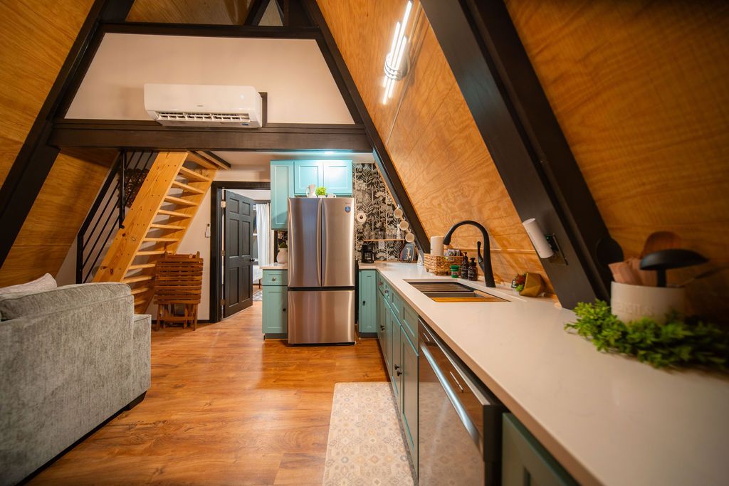 A modern kitchen with a central island, a built-in refrigerator, and a staircase leading to an upper level.
