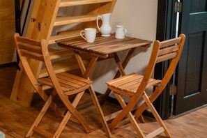 A wooden table with two chairs, a white pitcher, and a white mug on it.
