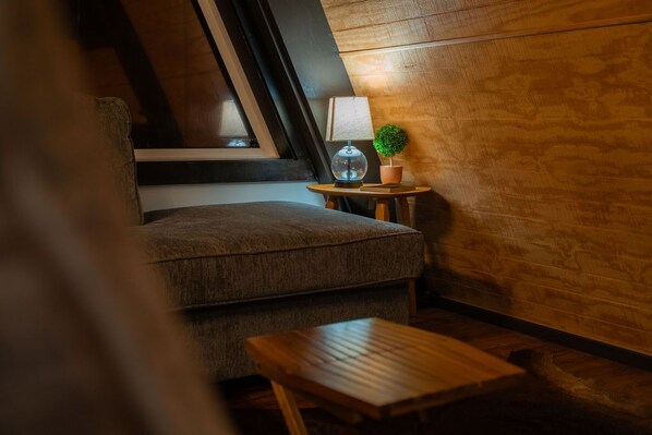 A cozy room with a sofa, a small wooden table, a lamp, and a potted plant.