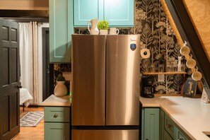 A kitchen with a stainless steel refrigerator, teal cabinets, and a patterned wallpaper.