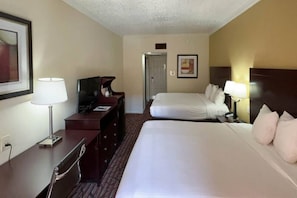A hotel room with a bed, a desk, a chair, a television, and a door. - 2 Queen Beds | Mobility Accessible Tub Nsmk (Dallas)