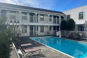 A hotel with a swimming pool, outdoor seating, and a two-story building with balconies. - 2 Queen Beds | Mobility Accessible Tub Nsmk (Dallas)
