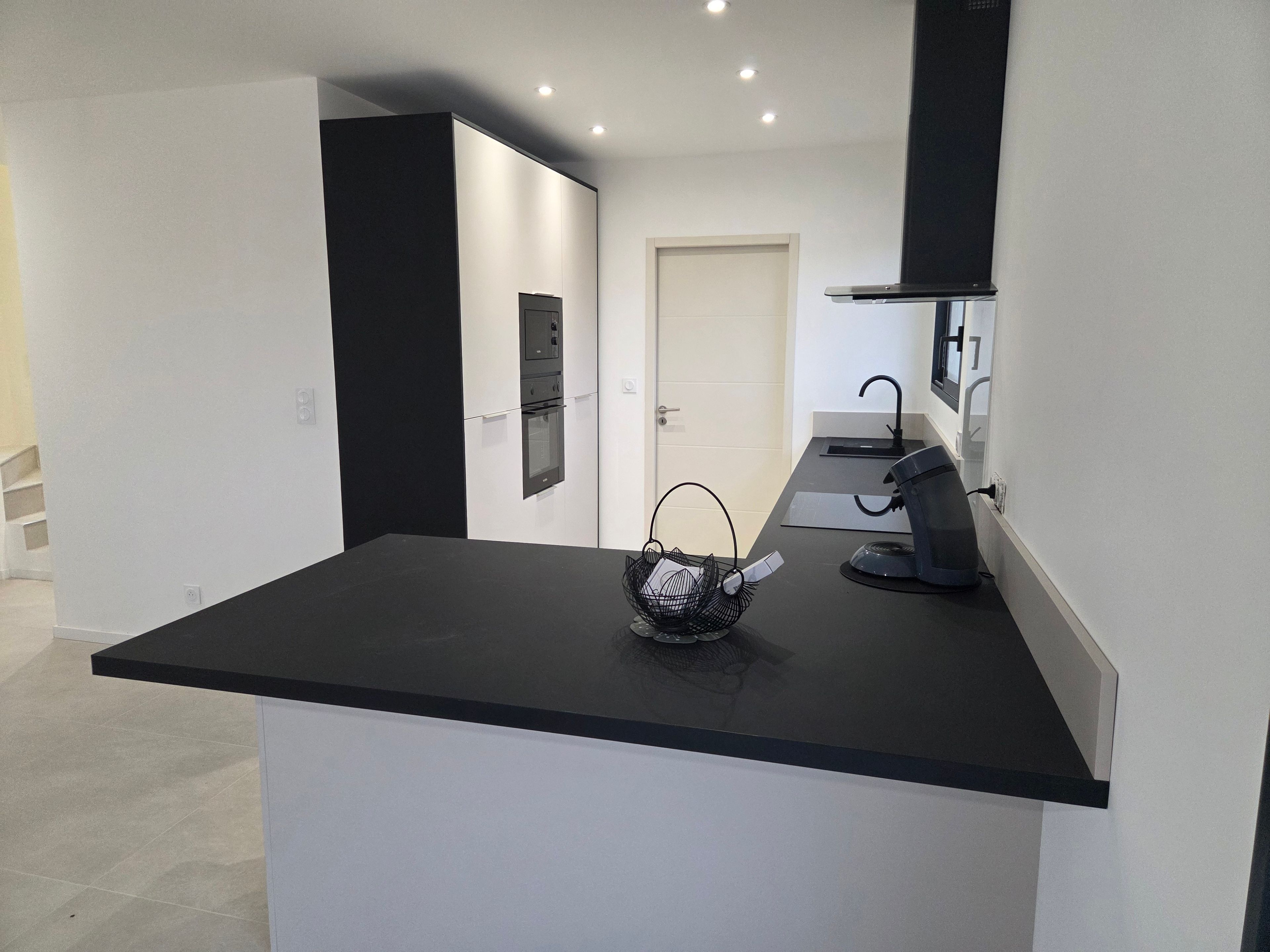 Eine moderne Küche mit schwarzem Arbeitsplatz, einer Kaffeemaschine und einem Korb voller Dokumente.