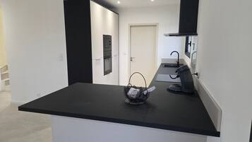 Eine moderne Küche mit schwarzem Arbeitsplatz, einer Kaffeemaschine und einem Korb voller Dokumente.
