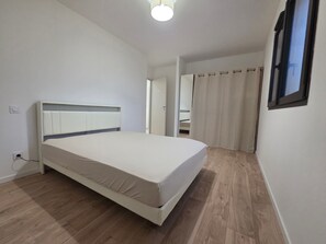 A bedroom with a bed, wooden flooring, a ceiling light, and a window with curtains. - Holiday Home 'La Villa De Jade' with Mountain View, Wi-Fi and Air Conditioning (Murles)