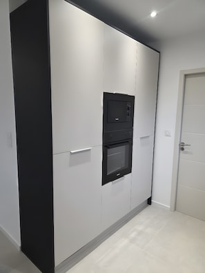 Cuina moderna amb electrodomèstics integrats, combinació de colors blanc i negre, i una porta a la dreta.