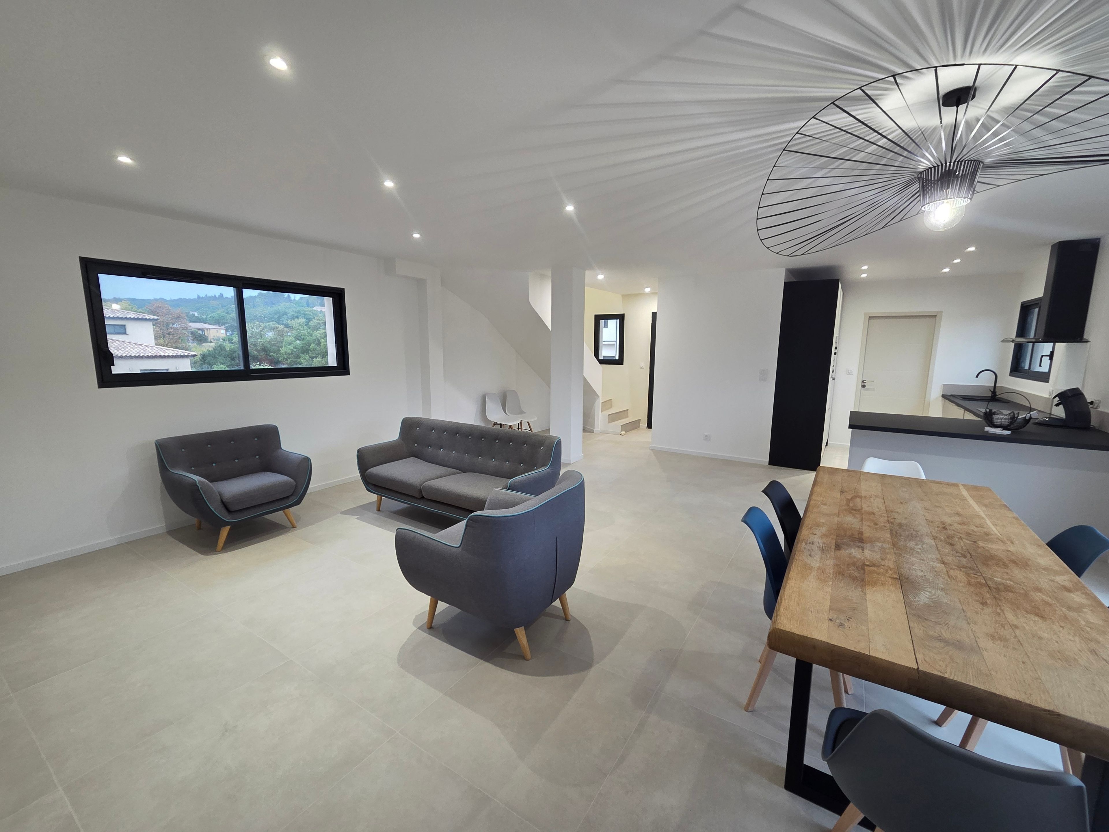 A modern interior with a dining area, sofas, a TV, and a kitchen.