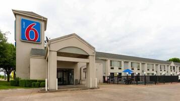 A 6 hotel with a single-story structure, a covered entrance, and a fenced parking area.