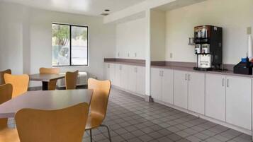 A clean, modern kitchen with white cabinets, a coffee machine, and a tiled floor.