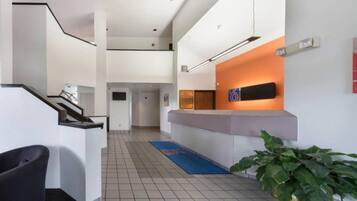 A modern reception area with a reception desk, a staircase, and a potted plant.