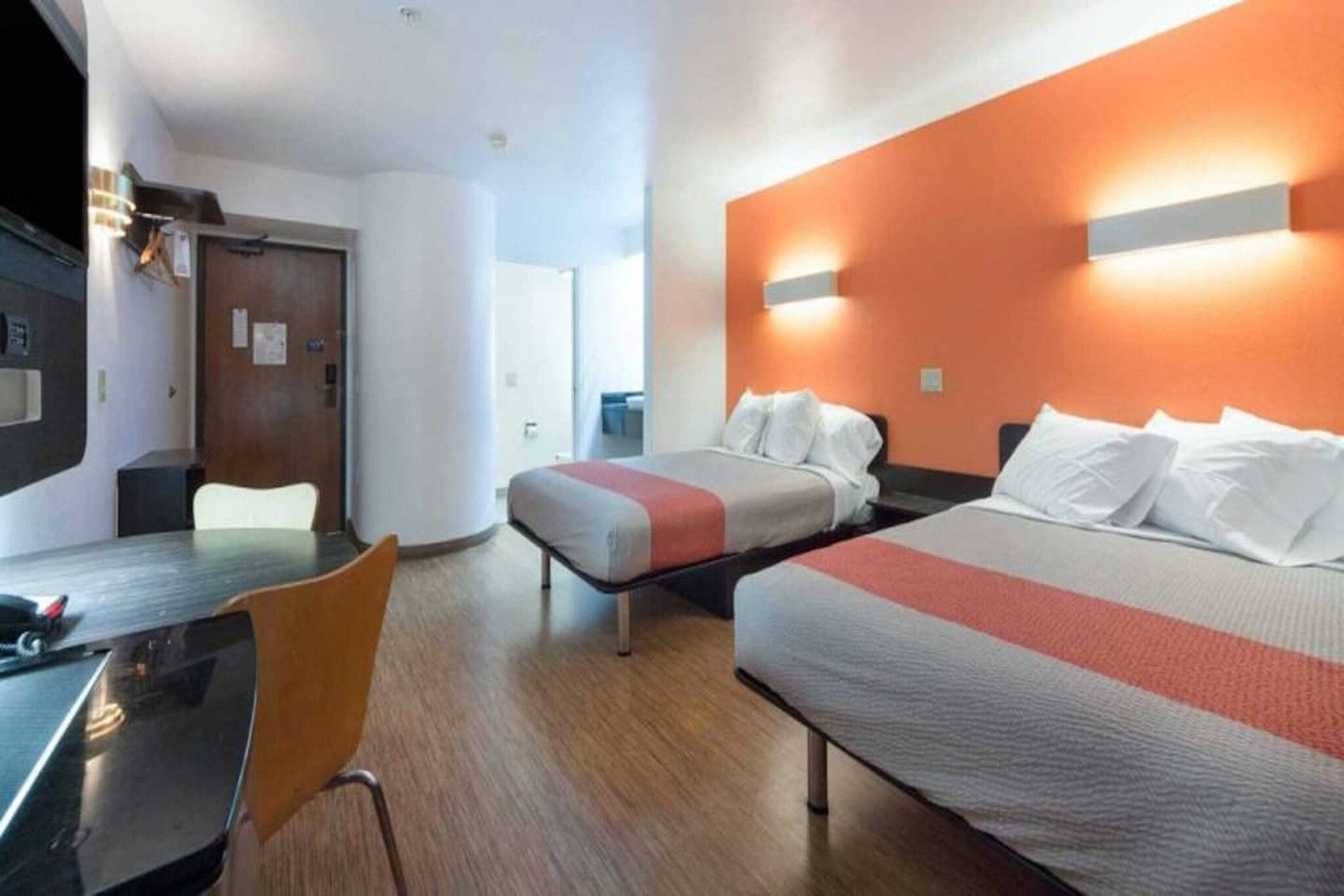 A hotel room with two beds, a desk, and a chair.