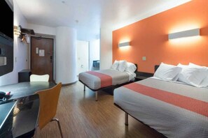 Une chambre d’hôtel avec deux lits, un bureau et une chaise.