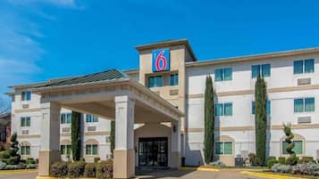 A multi-story hotel with a covered entrance and a prominent '6' sign.