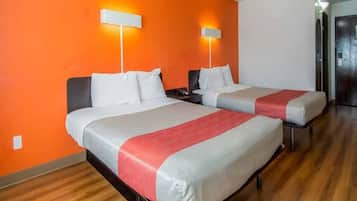 A hotel room with two beds, each with white bedding and a red accent.