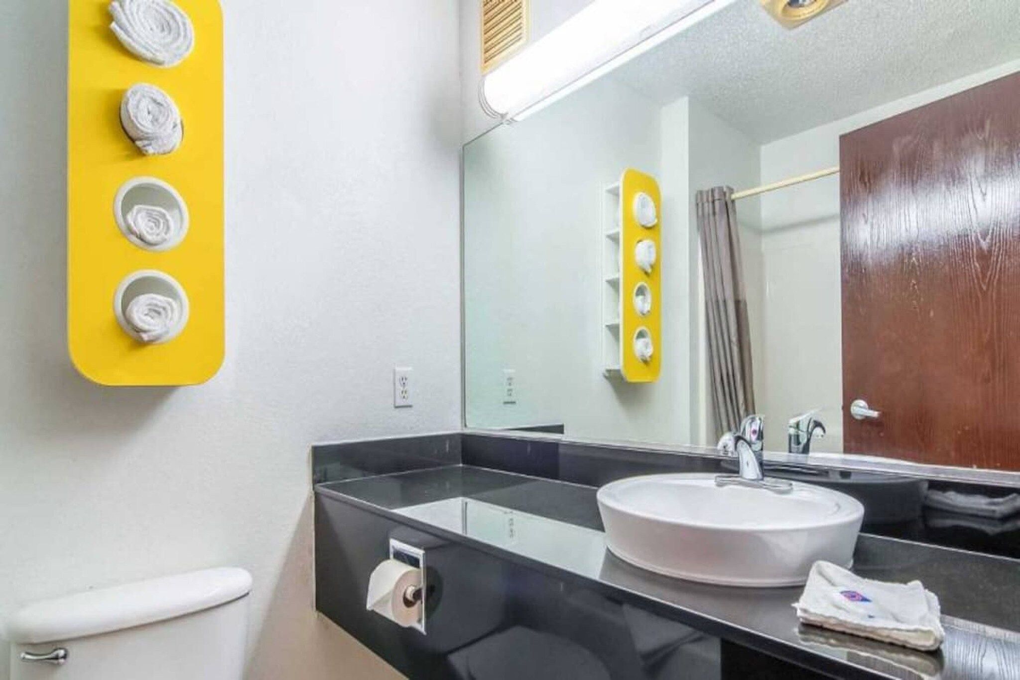 A bathroom with a sink, mirror, and a yellow soap dispenser.