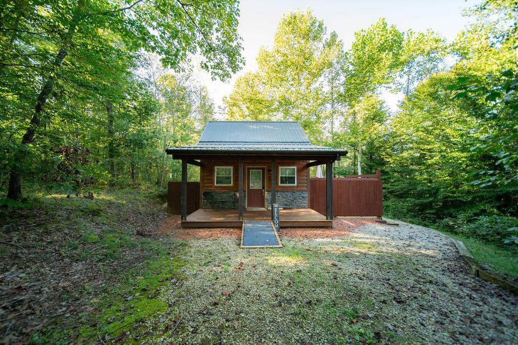 A cabin with a porch, surrounded by trees.