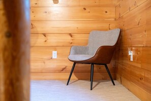 Ein Holzblockhaus-Innenraum mit einem einzelnen Stuhl an einer Holzwand.