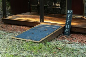A wooden deck with a welcome mat and a sign. - Turkey Trail | Hocking Hills, Hot Tub, Secluded (Logan)