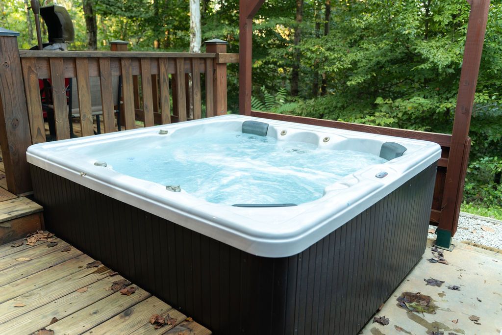 Ein Whirlpool auf einer Holzdiele, umgeben von viel Grün.