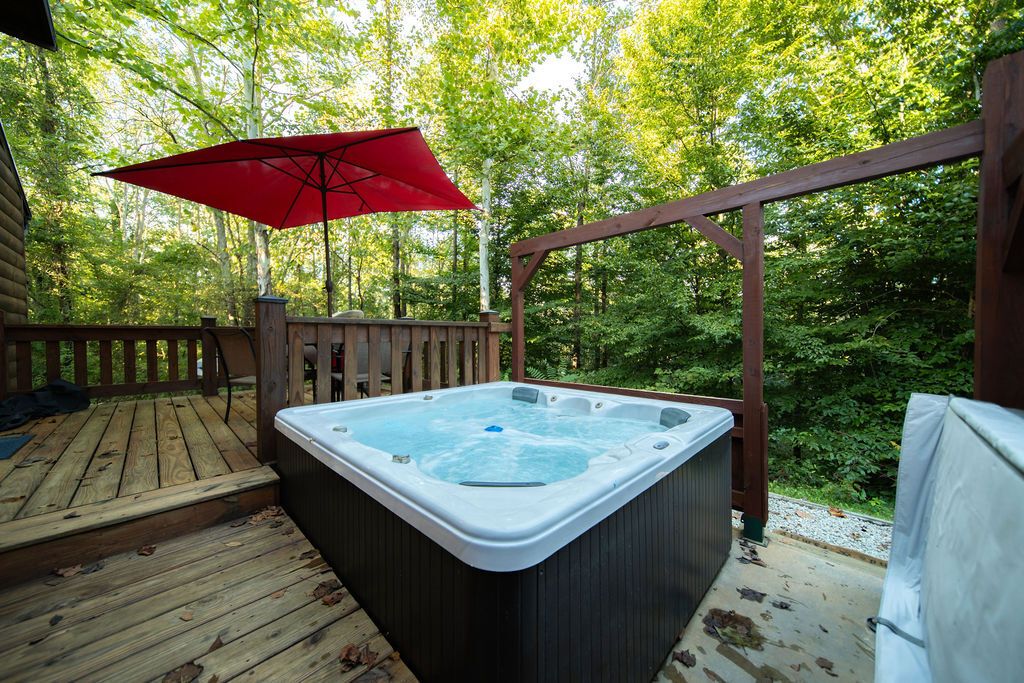 Ein Whirlpool auf einer Holzterrasse mit einem roten Sonnenschirm.