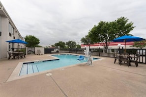 A swimming pool with a lifeguard chair and a small inflatable boat, surrounded by lounge chairs and umbrellas. - 1 Full Bed|ADA/RI Shower,Nsmk (Dallas)