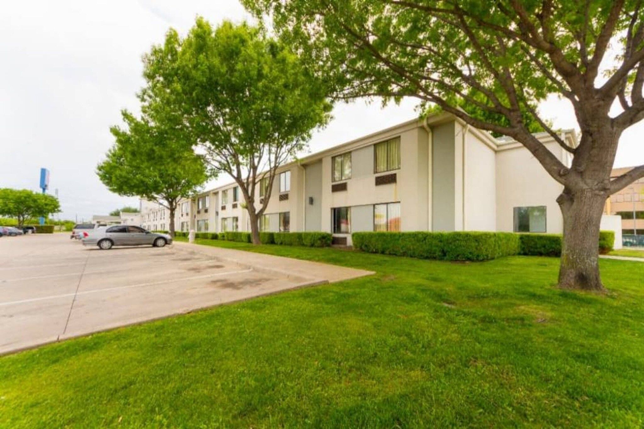 A modern apartment building with a parking lot and well-maintained lawns.