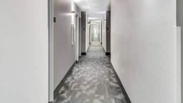A long, straight hallway with doors on both sides, leading to rooms. The floor has a patterned tile design.