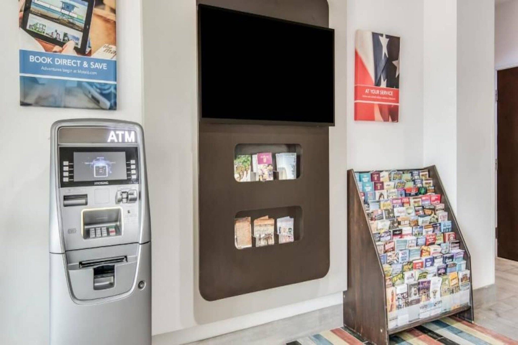 An ATM machine, a book display, and a sign promoting a service.