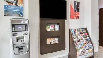 An ATM machine, a book display, and a sign promoting a service.