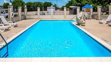 A rectangular swimming pool with a no diving sign, surrounded by lounge chairs and a covered area.
