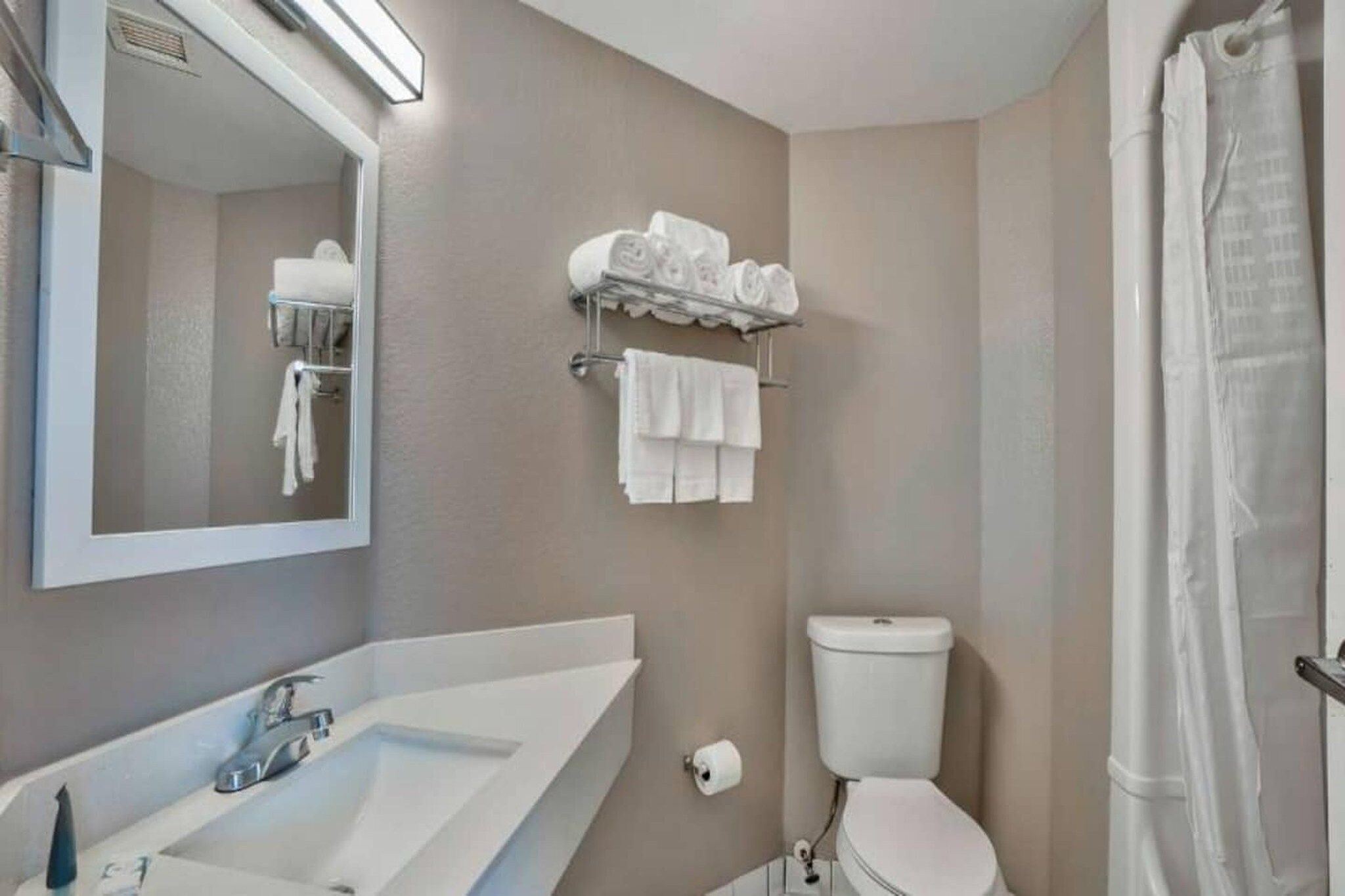 Een badkamer met een wastafel, spiegel, toilet en handdoekhouder.