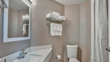 Een badkamer met een wastafel, spiegel, toilet en handdoekhouder.
