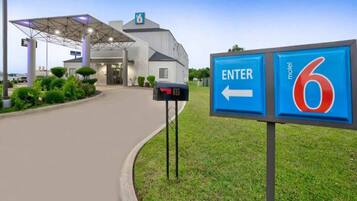 Un motel con un cartello d'ingresso ben visibile, una cassetta postale e un prato curato.