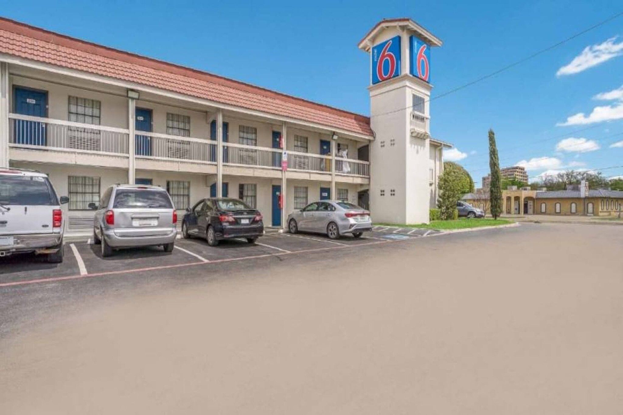 Un motel doté d’un parking, d’un bâtiment à deux étages et d’une tour sur laquelle est inscrit le chiffre 66.