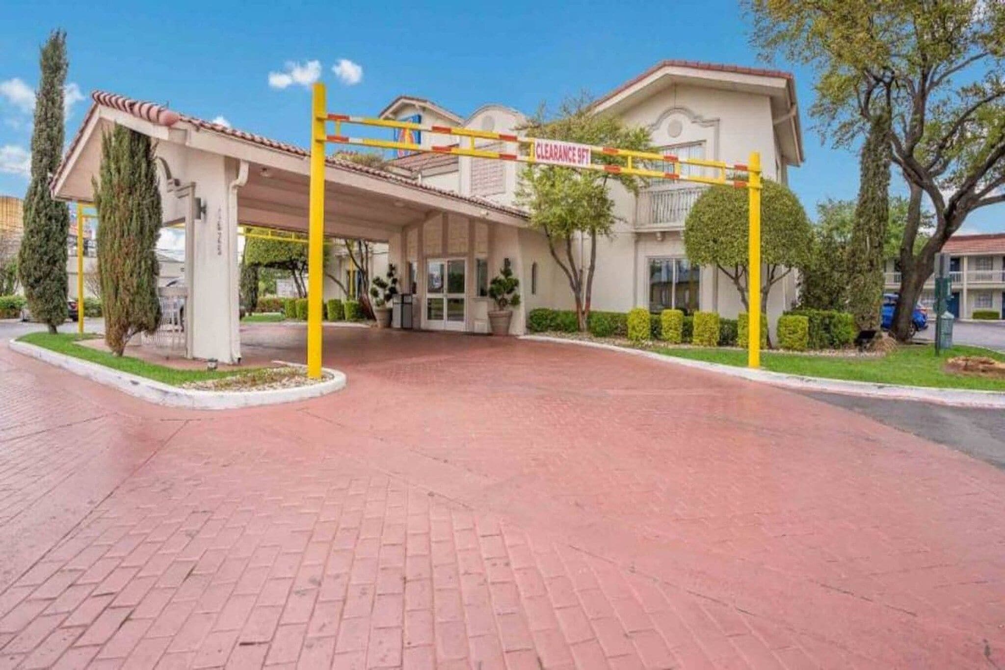 A building with a covered entrance, a yellow barrier, and a sign indicating a clearance of 9 feet.