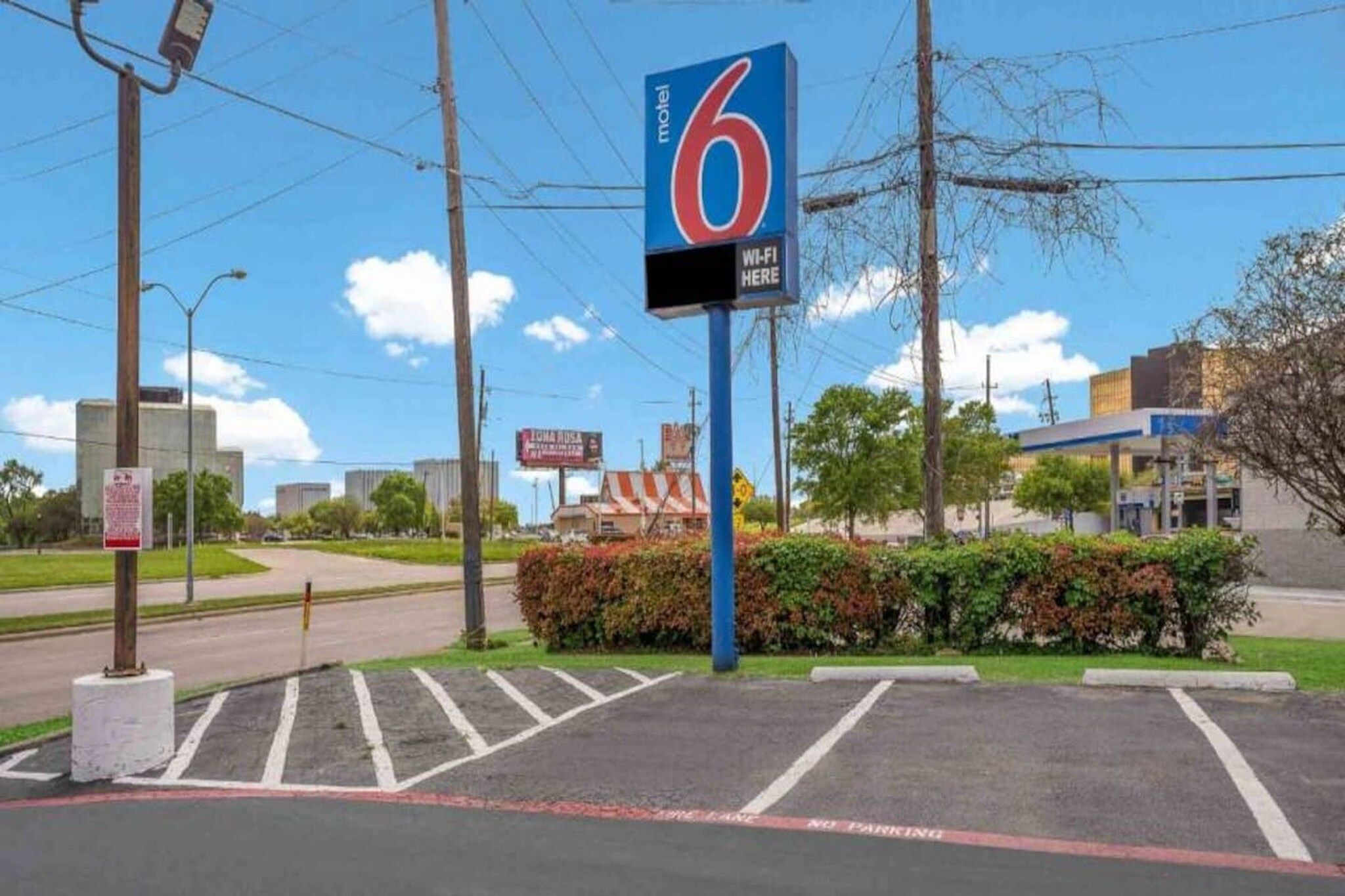A motel sign with a '6' logo, a parking lot, and a building in the background.
