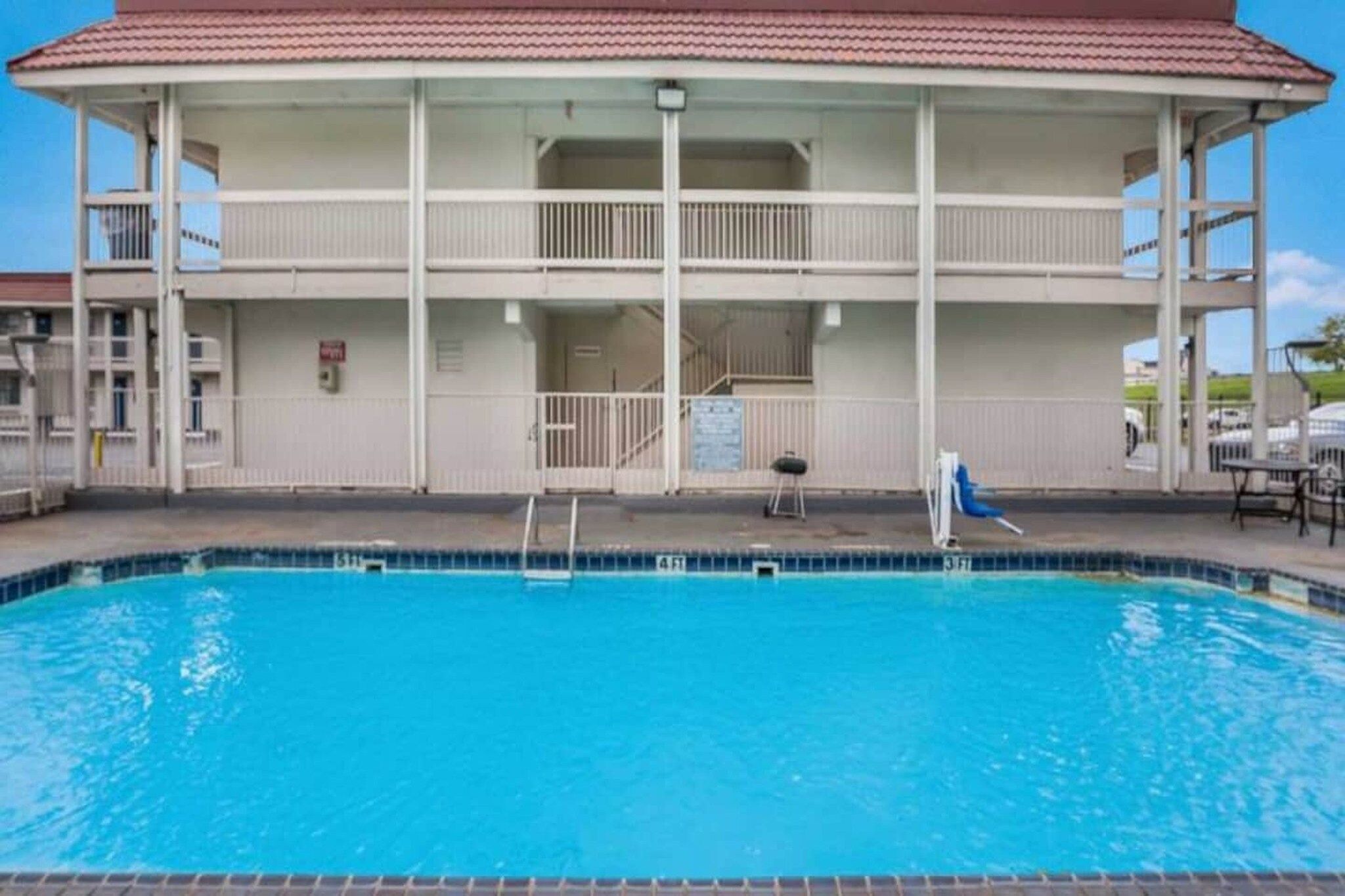 Un bâtiment à deux étages avec une piscine devant.