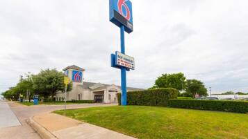 A motel with a prominent blue sign, an exit sign, and a building entrance.