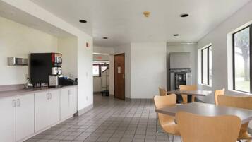 A spacious indoor area with a kitchen counter, a refrigerator, and a dining table with chairs.