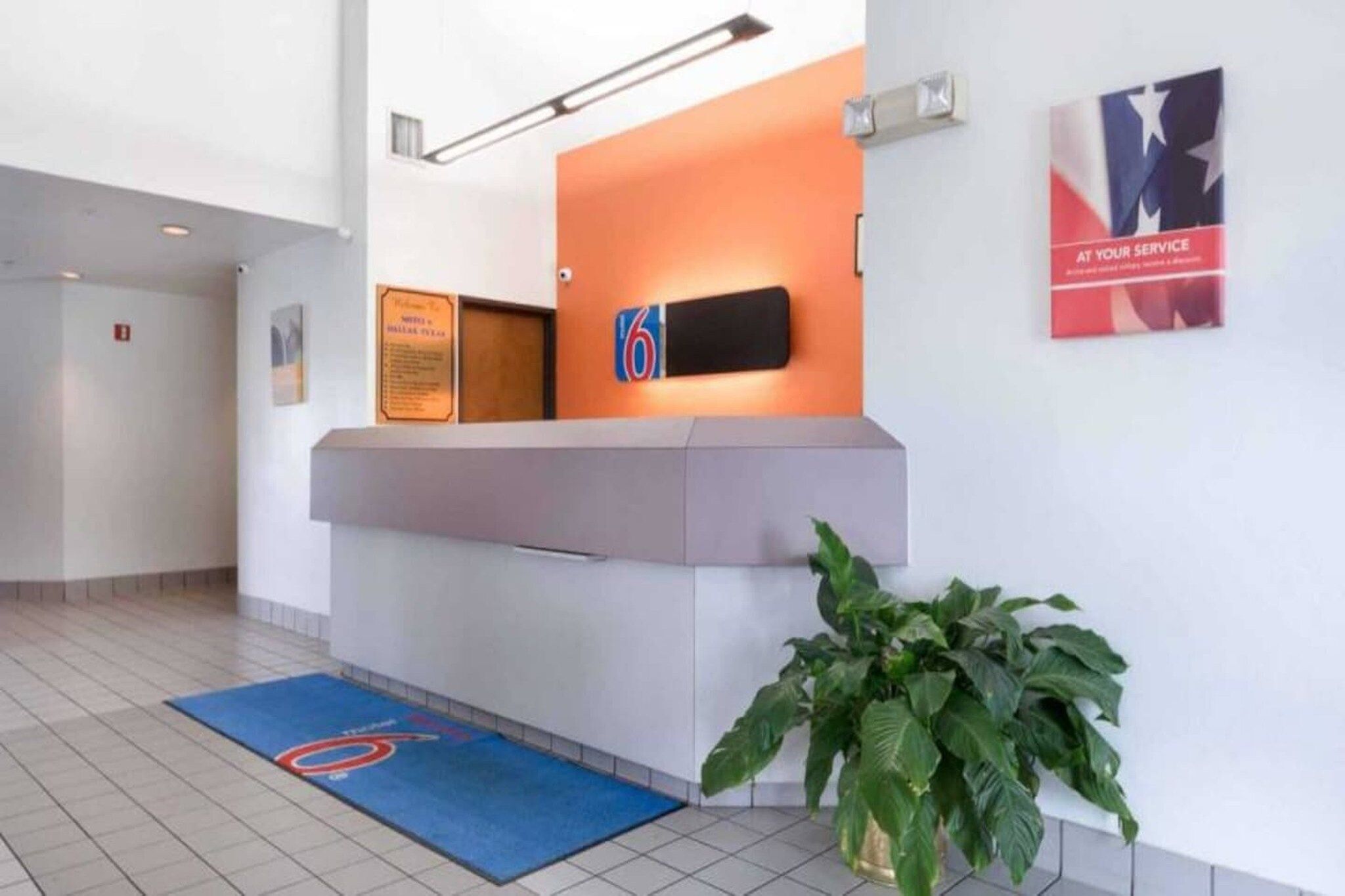 A reception area with a counter, a sign with the number 6, and a plant.