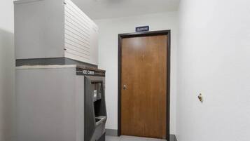 A room with a refrigerator, an ice dispenser, and a wooden door with a 'telephone' sign above it.