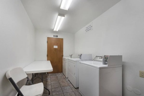 A small laundry room with a table, chairs, a washing machine, and a dryer. - 1 Queen Bed | Non-Smoking (Dallas)
