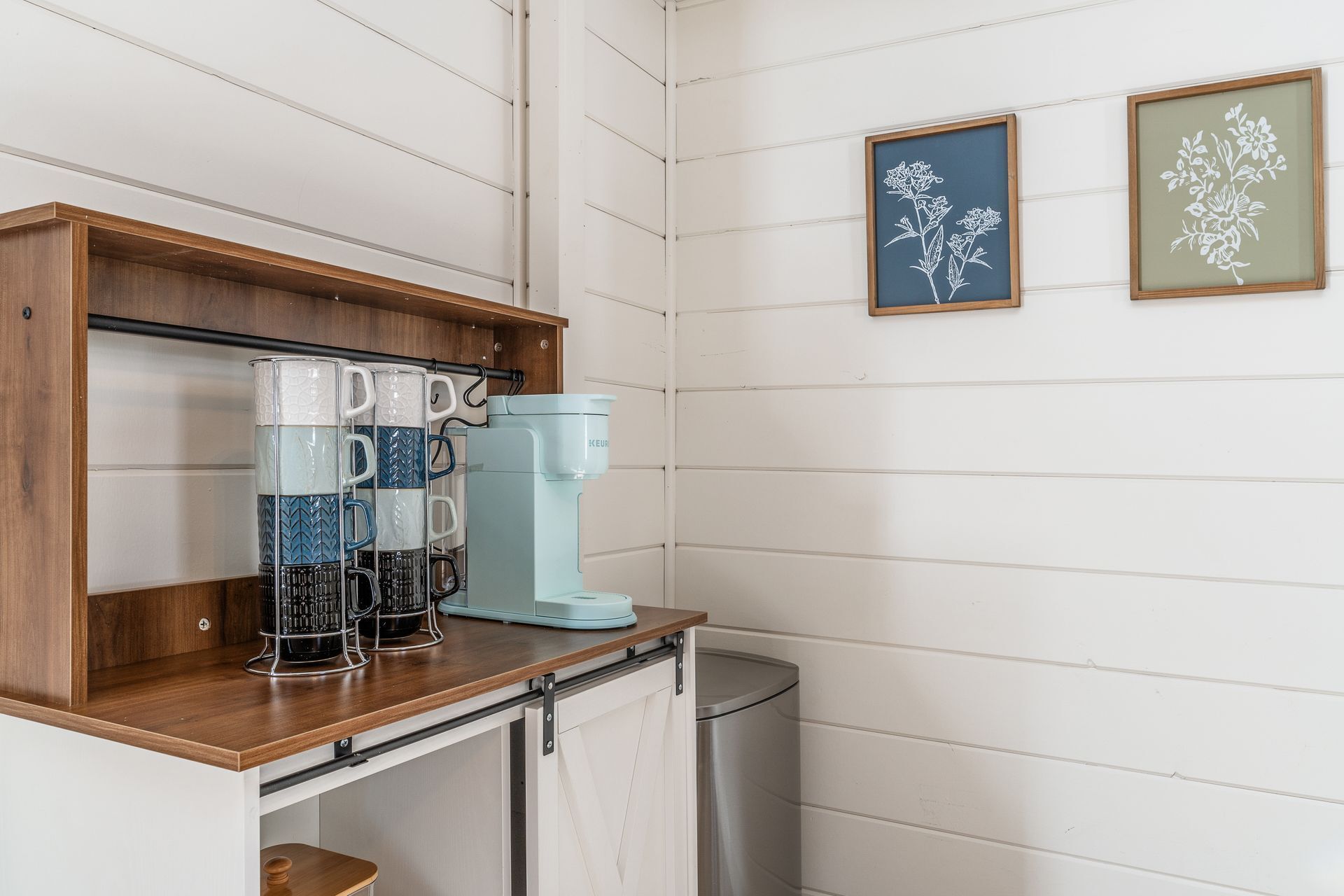 A kitchen with a wooden countertop, a coffee maker, and a trash can.
