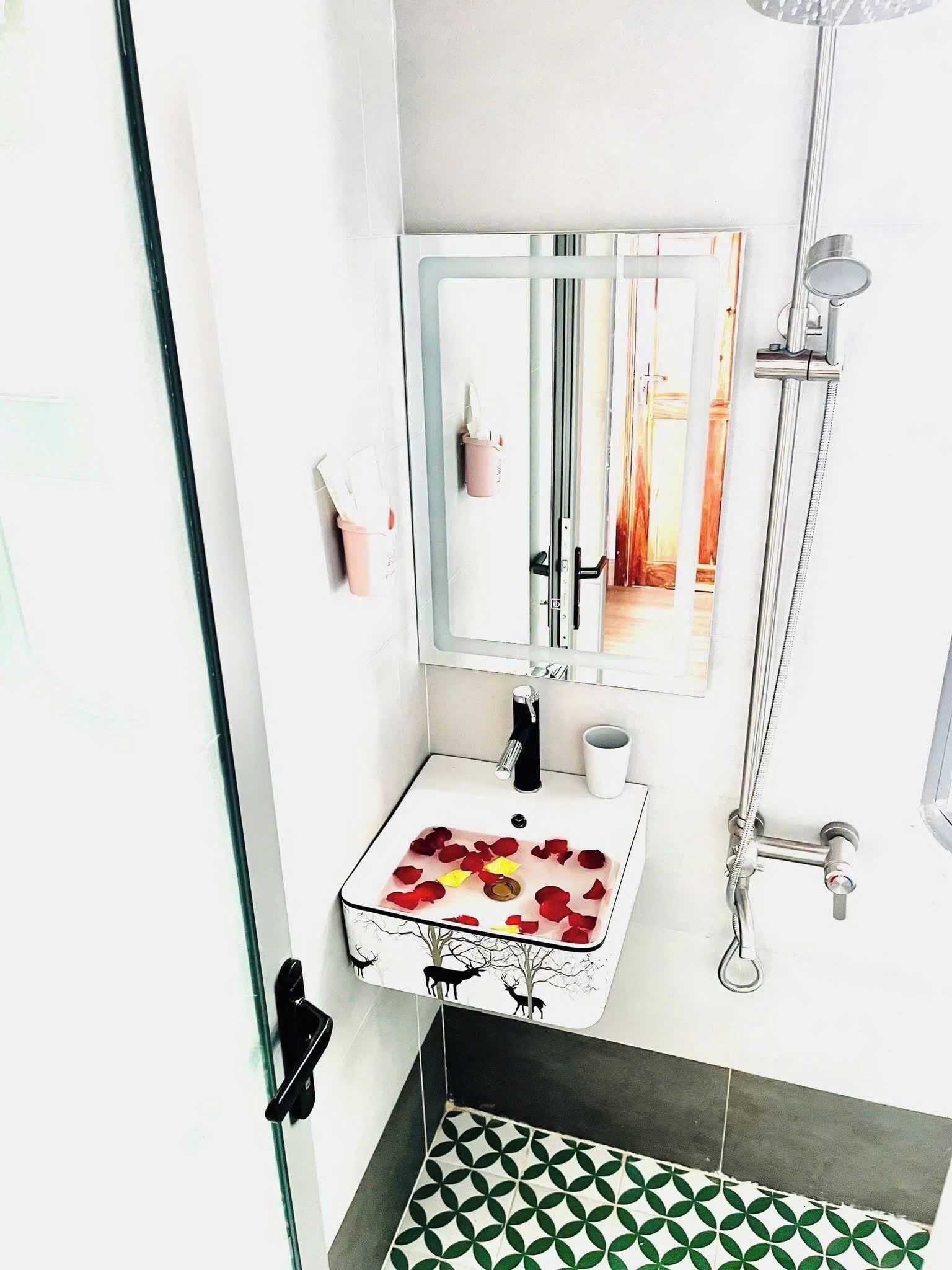 Ein Badezimmer mit einem weißen Waschbecken, einem Spiegel, einer Dusche und einem gemusterten Boden.