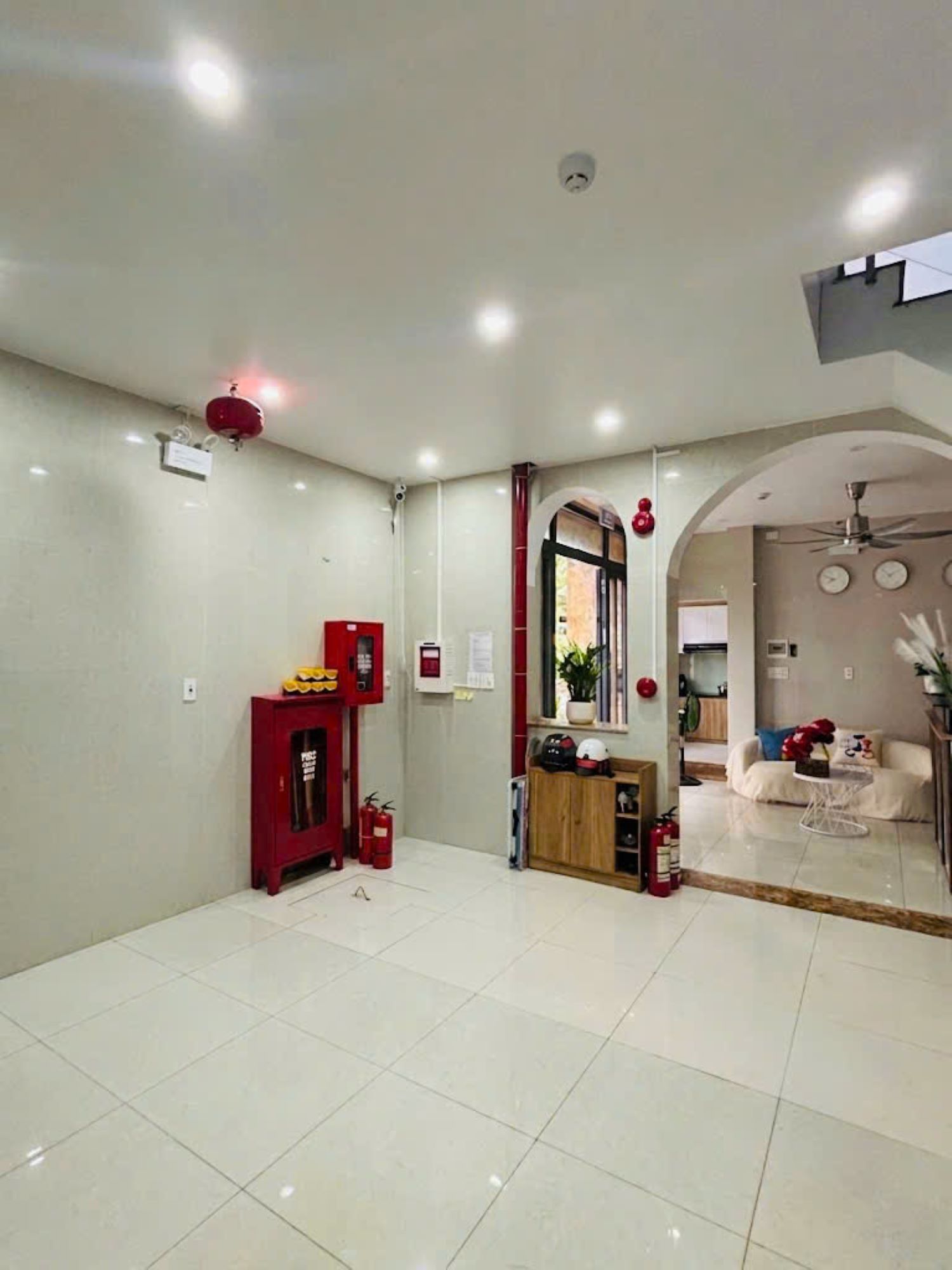 Une pièce spacieuse avec un sol carrelé, un meuble rouge, un ventilateur de plafond et une fenêtre donnant sur un beau paysage.