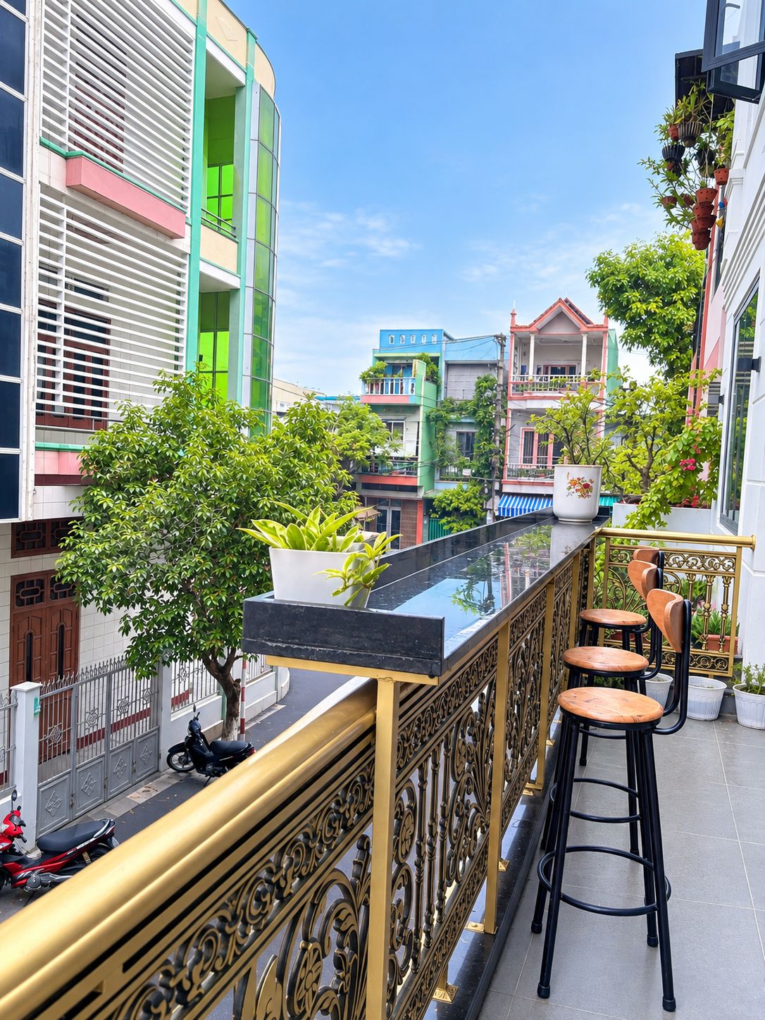 A balcony with a glass barrier, a small tree, and a seating area with stools.